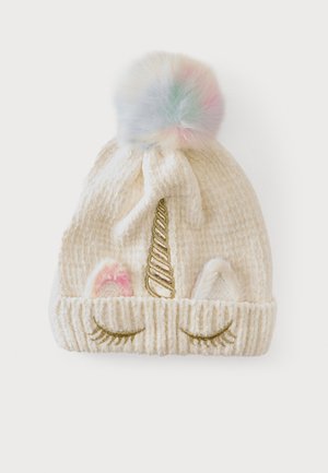 Bonnet tricoté crème avec un pompon multicolore, une corne de licorne dorée, des oreilles roses et blanches, et des yeux fermés brodés sur le revers.