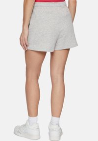 Pantaloni corti in cotone grigio con una vestibilità rilassata, vita elastica e texture liscia, abbinati a sneakers bianche e calze a coste fino alla caviglia.