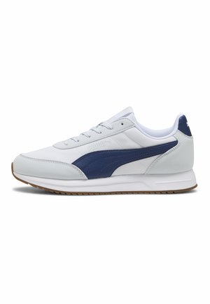 Sneaker Puma bianca e blu navy con design con lacci, suola imbottita e suola esterna in gomma mostrata di profilo.