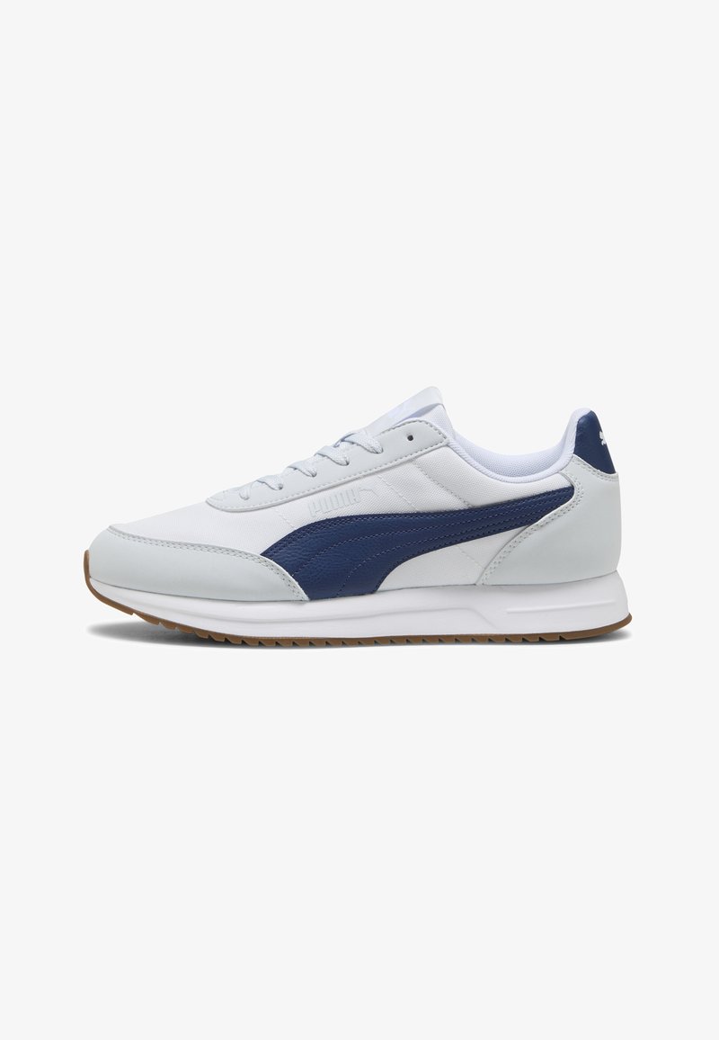 Baskets Puma blanches et bleu marine avec fermeture lacée, semelle rembourrée et semelle extérieure en gomme, vues de profil.