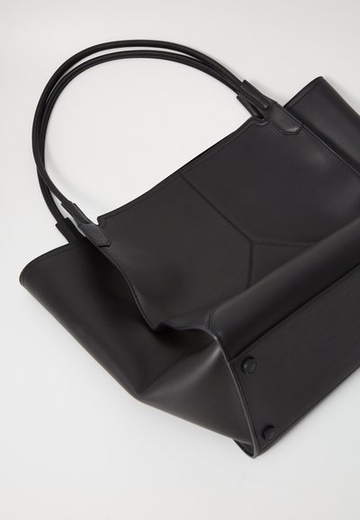 Sort læder tote taske med dobbelte håndtag, glat tekstur og struktureret form. Har fold-over design og synlige søm detaljer.