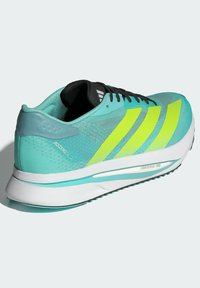 Scarpa da ginnastica di un blu chiaro con una parte superiore in mesh, lacci neri e tre audaci strisce gialle. Presenta un'intersuola bianca e blu chiaro etichettata "LIGHTSTRIKE PRO."