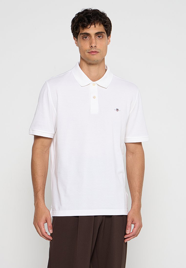 Weißes Poloshirt aus Baumwolle mit klassischem Kragen, dreiknöpfiger Knopfleiste und kurzen Ärmeln mit kontrastierenden Bündchen. Kleines Logo auf der Brust.