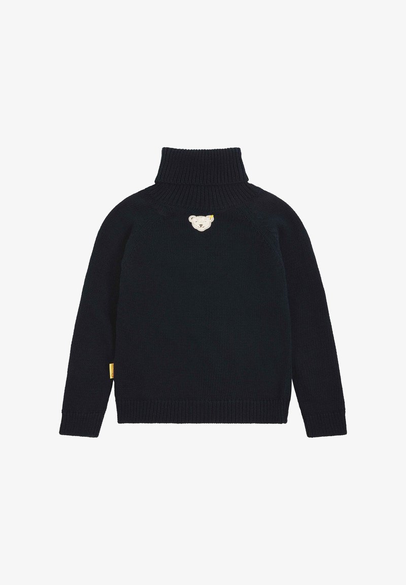 Pull noir à col roulé en tricot avec manches longues et petite pièce représentant un ours en peluche blanc centrée sur la poitrine.
