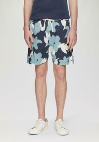 Heren zwembroek in marineblauw met witte en aqua bloemenpatronen. Gemaakt van lichtgewicht stof, met een elastische tailleband en koord.
