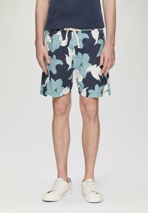 Shorts de bain pour hommes en bleu marine avec des motifs floraux blancs et aqua. Fabriqués en tissu léger, dotés d'une taille élastique et d'un cordon de serrage.