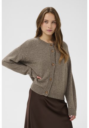 Pruun kootud kardigan ümara kaelusega, millel on suured puidust nööbid ja heledad metallikniitidetailid üle kogu pinna. Liiga suur lõige.