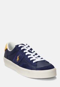 Navy blue sneaker with suede and leather materials, white laces, and distinct yellow heel accent. Features logo embroidered on side.