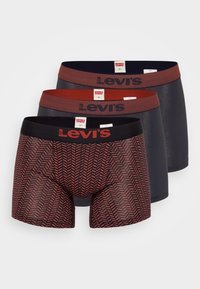 Tre par Levi's boxershorts: en med ett rött fiskbensmönster, en i mörkröd färg och en i svart. Alla har elastiska midjeband.