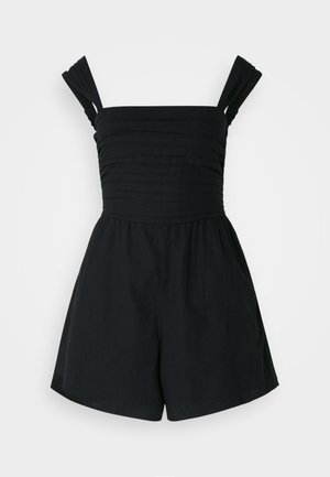 Mustmustöörne musta värvi asja, millel on muljetavaldavad laiad pleeditud õlapaelad, istuv bodi ja lõdvad lühikesed püksid. Valmistatud kergest materjalist, millel on sile tekstuur.