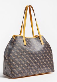 Brązowa torba na ramię w wzory z żółtymi skórzanymi akcentami. Posiada grube uchwyty i przestronny design, prezentujący strukturalną sylwetkę.