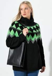 Černý svetr se zelenými a šedými geometrickými vzory, vysoký rolák, doplněný černou koženou taškou, v kombinaci s modrými džíny.