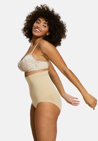 Shapewear beige a vita alta con un reggiseno in pizzo trasparente. Texture liscia, senza hardware visibile. La modella posa di profilo, mettendo in evidenza vestibilità e design.