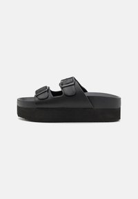 Black platform sandals made of smooth material, featuring two adjustable straps with buckles, and a textured sole for grip.