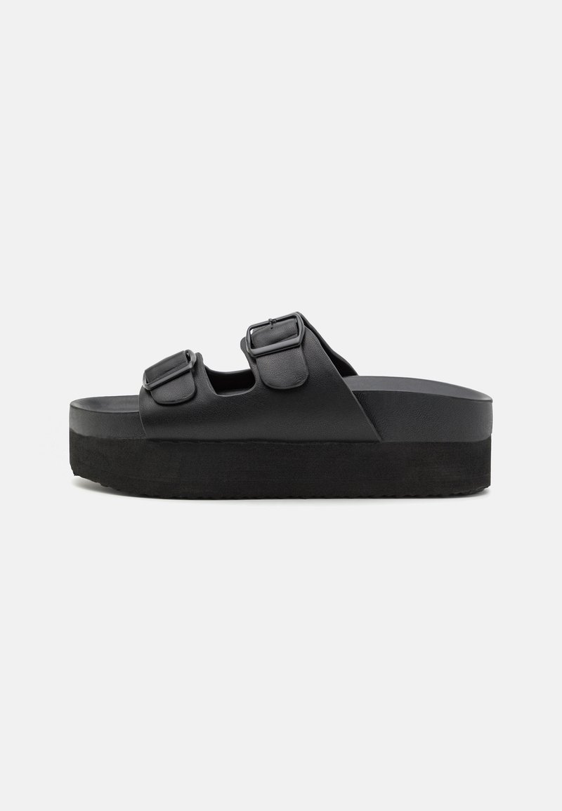 Black platform sandals made of smooth material, featuring two adjustable straps with buckles, and a textured sole for grip.