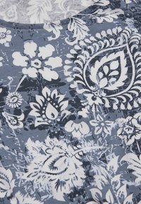 Blått och vitt tyg med ett blommönster och paisleym önster, med olika stiliserade blommor och blad i en tät dekorerande design.