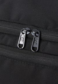 Black fabric bag featuring two metallic zipper pulls, textured surface, and reinforced stitching along the seams.