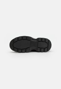 Suela de goma negra con patrón de agarre texturizado, que presenta crestas y surcos para tracción. Superficie plana con bordes redondeados.