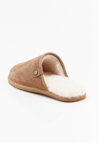 Pantofole in suede marrone con un interno morbido color crema, design aperto sul retro, punta rotonda e un dettaglio decorativo con bottone sul lato.