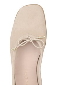 Beżowy aksamitny baletka z kwadratowym noskiem, ozdobną kokardą z złotymi metalowymi końcówkami na górze oraz złotym napisem "RICKIT" wewnątrz.