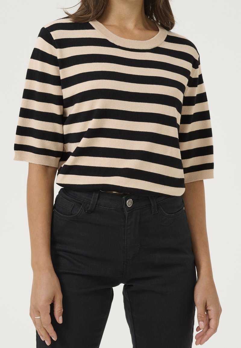 Stribet striktrøje i beige og sort, korte ærmer, rund halsudskæring, blød tekstur. Kombineret med sorte slim-fit jeans, metalknapdetalje.
