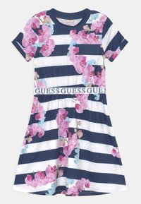 Námořnické a bílé pruhované šaty s růžovým květinovým vzorem orchidejí a logem na pasu. Krátké rukávy a design do zvonu sukně.