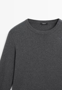 Pull gris à col rond en tissu doux. Doté de manches longues et d'un design simple. Étiquette visible au niveau du col.