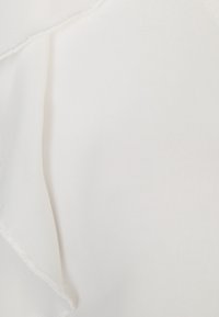 Tessuto bianco con una texture liscia e una caduta morbida, con un delicato bordo arricciato e una sottile cucitura lungo la cucitura.