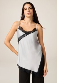 Satinagtig grå camisole med sort blondetrim langs udskæringen og asymmetrisk kant, med tynde justerbare stropper og indviklede blonde detaljer.