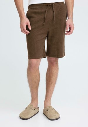 Brune shorts med vaffeltekstur, elastisk midjebånd og snor, med sidelommer. Brukt med beige slip-on sko.