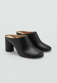 Mules de cuero negro con acabado suave, punta afilada y tacón cuadrado. El diseño es abierto por detrás para facilitar su uso.