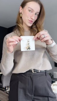 Silver and gold layered earrings displayed on a white card, featuring a geometric pendant and polished metallic accents.