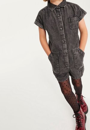 Czarny dżinsowy kombinezon szorty z kołnierzykiem, zapinany na guziki, z kieszonką naszywaną, zestawiony z pończochami w kropki i czerwonymi botkami za kostkę.