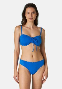 Set di bikini blu con un design a onde, spalline regolabili e un dettaglio annodato sul davanti del top, abbinato a uno slip con bordo ondulato.