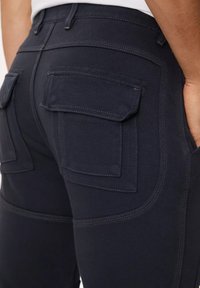 Pantaloni navy con doppie tasche posteriori, cuciture in contrasto e un design aderente con una texture liscia.