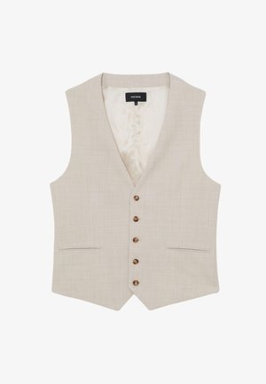 Man die een beige vest en broek draagt met een lichtblauw gestreept overhemd, van achteren afgebeeld tegen een witte achtergrond.