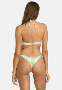 Wielokolorowy zestaw bikini z kwiecistymi wzorami, z modelem na szyję, regulowanymi ramiączkami oraz minimalnym zakryciem w kroku.