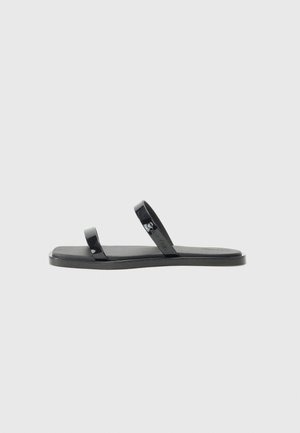 Black flip-flop sandals with two glossy, flat straps and a textured, matte footbed. Modern, minimalist design suitable for casual wear.