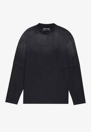 Langermet svart t-skjorte laget av mykt materiale; har rund hals, løs passform og svak gradienteffekt fra lys til mørk.