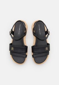 Czarne skórzane sandały z dwoma szerokimi paskami, złotym logo i teksturowaną beżową platformą. Posiadają regulowany pasek na kostkę.