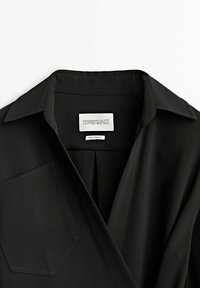 Mustassa paidassa on taitettu kaulus, jossa on läpällinen rintatasku ja "MASSIMO DUTTI LIMITED EDITION" -tarra. Silkkinen kangas.