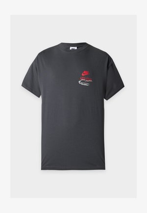 Σκούρο γκρι κοντομάνικο Nike T-shirt με κόκκινο κείμενο "Nike Arts Club" και λευκό γραφικό στο αριστερό στήθος.
