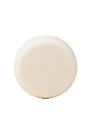 Round, solid, cream-colored bar with a smooth, matte surface and slight texture imperfections, resembling natural soap or body care product.
