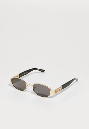 Occhiali da sole con montatura dorata, lenti scure, forma ovale e aste nere con un distintivo dettaglio del logo dorato.