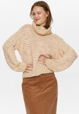 Fleeciger Pullover mit pinken Sprenkeln, hohem Kragen und gerippten Bündchen. Tragen mit einem braunen Cordrock. Strukturiertes Strickmuster durchgehend.
