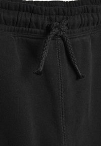 Schwarze Jogginghosen mit einem strukturierten elastischen Bund und einem geflochtenen Kordelzug sowie sichtbaren Nähten für Haltbarkeit.
