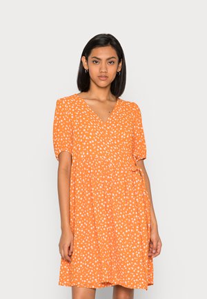 Vestido envelopado laranja com mangas curtas, poás brancos, decote em V e detalhe de laço na cintura. Tecido fluido com um corte descontraído.