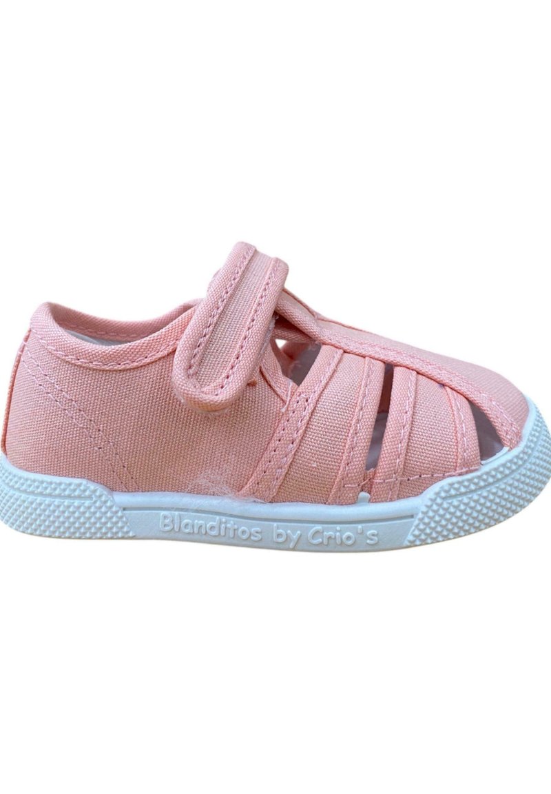 Zapato de tela rosa con punta cerrada y cortes laterales abiertos. Cuenta con una correa de velcro y una suela de goma blanca texturizada con marca.