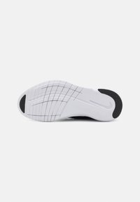 Semelle blanche de chaussure de sport avec zones de grip noires au talon et aux orteils et fines lignes noires en grille sur l'avant-pied.