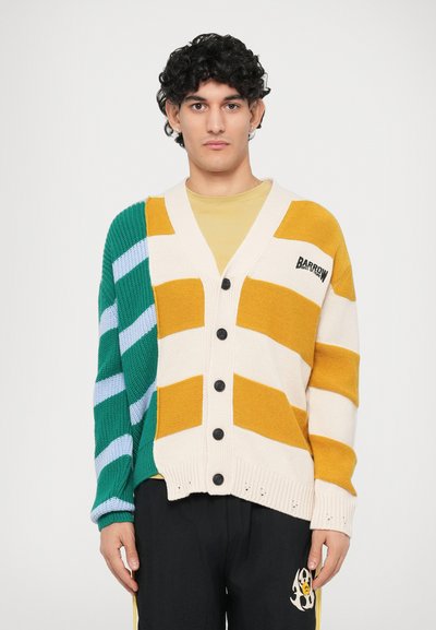 Cardigan tricoté avec des rayures multicolores en vert, jaune et crème, avec un col en V, une fermeture à boutons et des manches texturées.